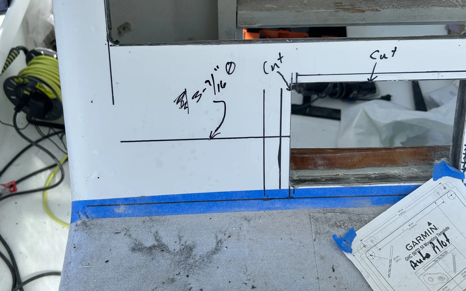 Marked cut lines and a Garmin autopilot mounting template staged before cutting the console