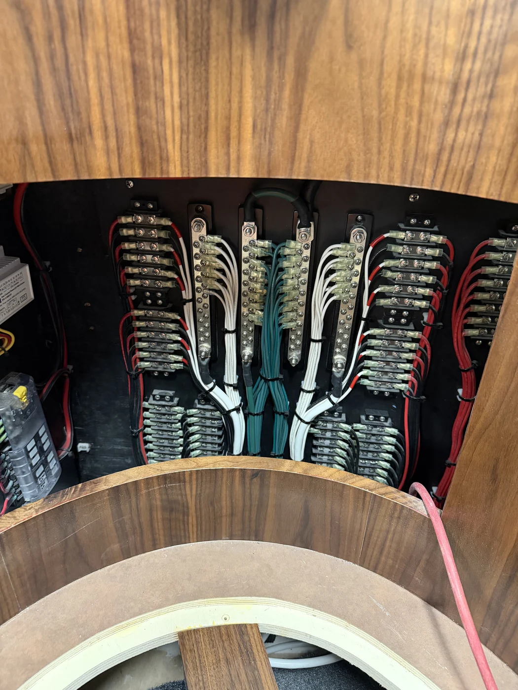 Labeled terminal strips and bus bars wired beneath a curved helm window during a vessel refit