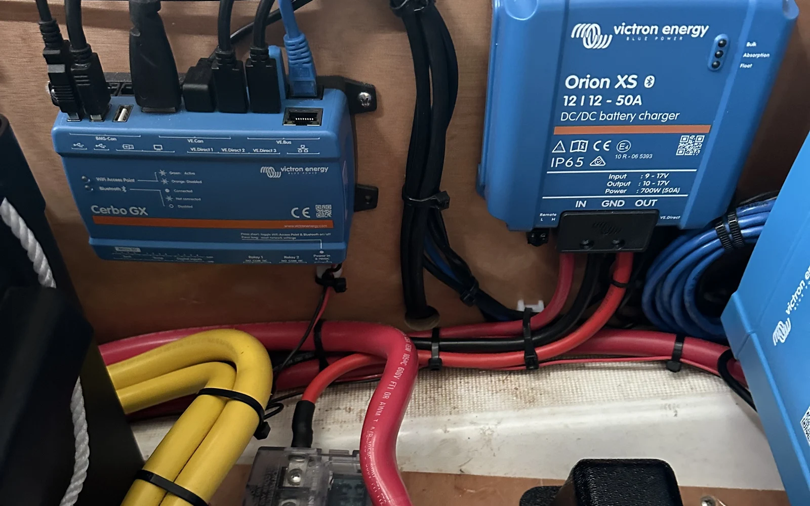 A Victron Cerbo GX monitor and Orion XS DC-DC charger wired together on a distribution panel