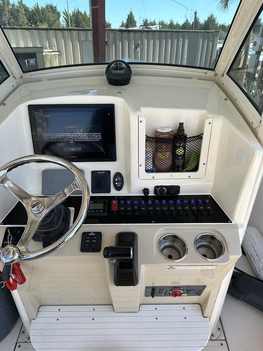 A center console helm with Garmin chartplotter, compass, and labeled accessory switches