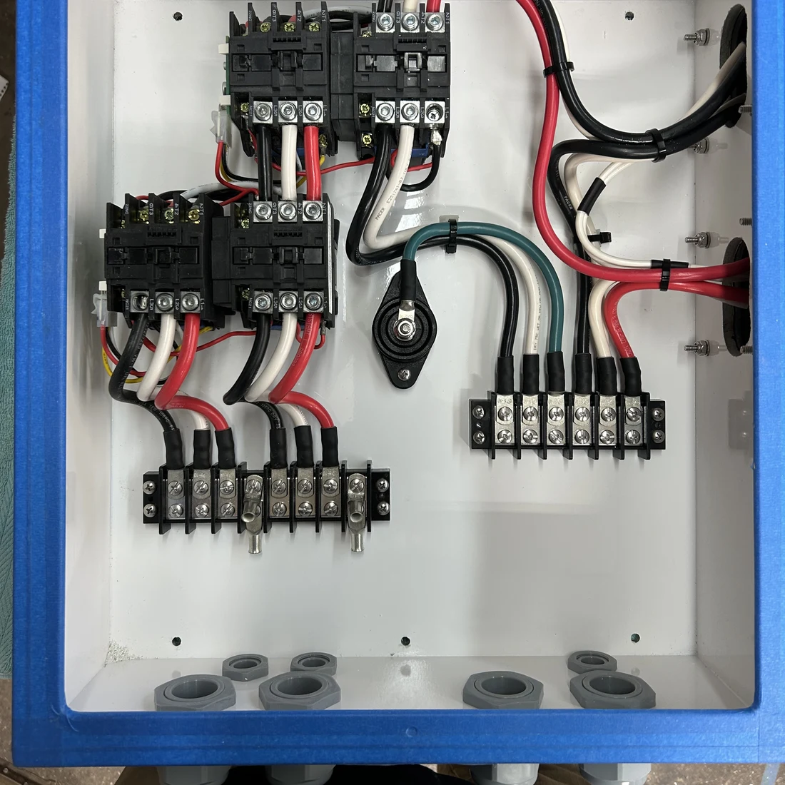 A distribution box interior with contactors wired to labeled terminal blocks