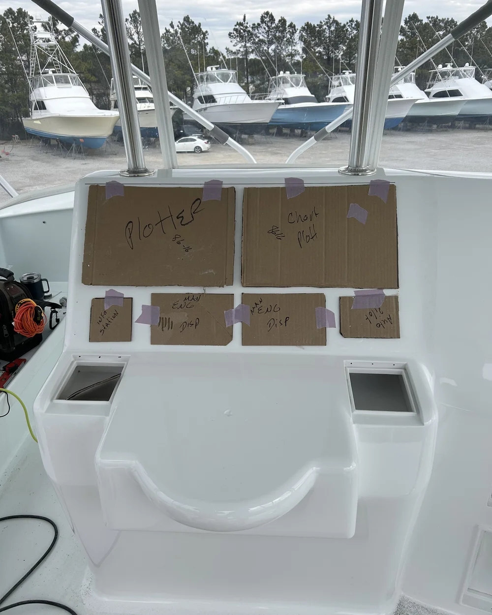 Cardboard templates taped to a helm console mapping planned chartplotter and instrument cutouts before installation