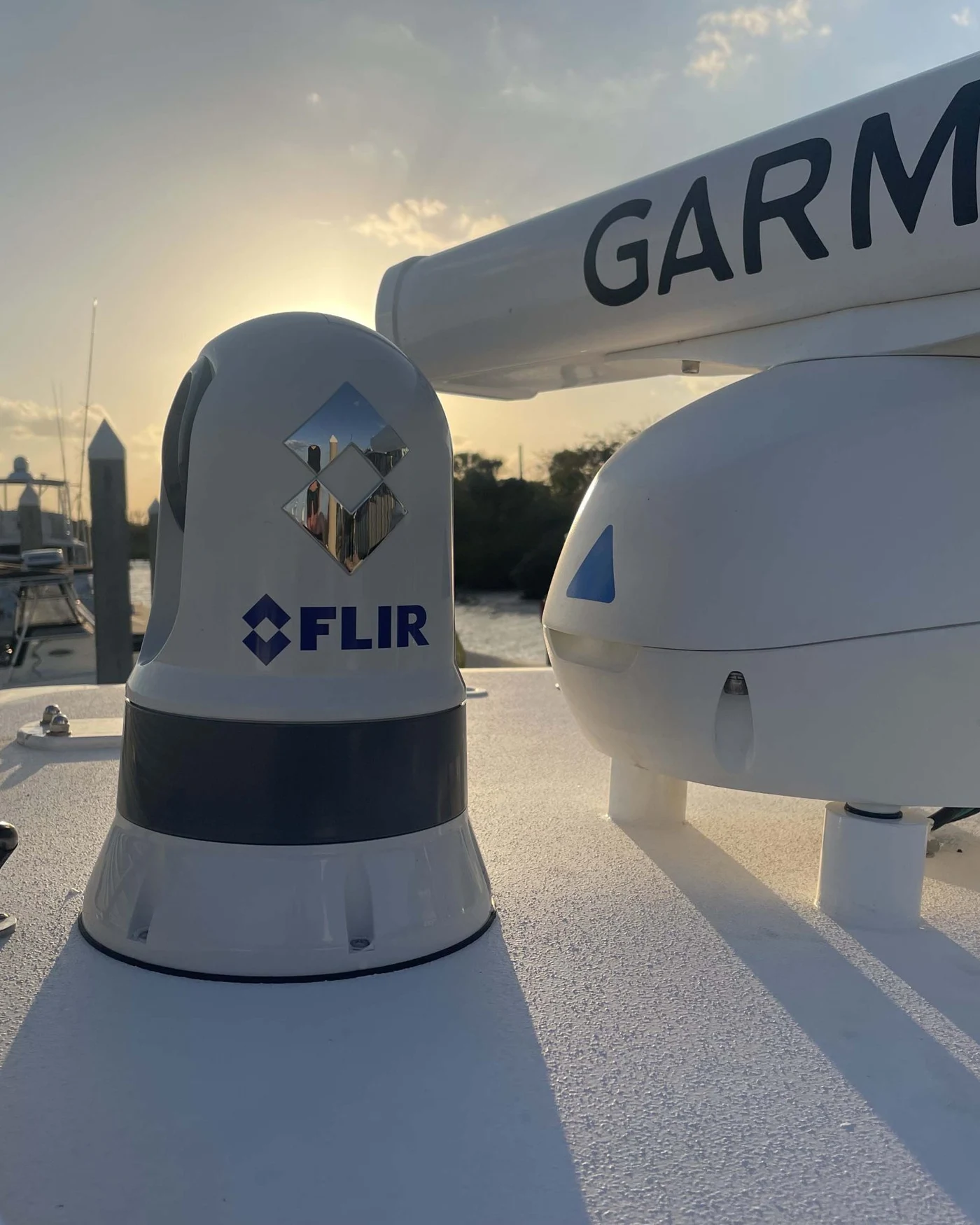A FLIR camera dome and Garmin radar dome mounted on a boat's hardtop at sunset