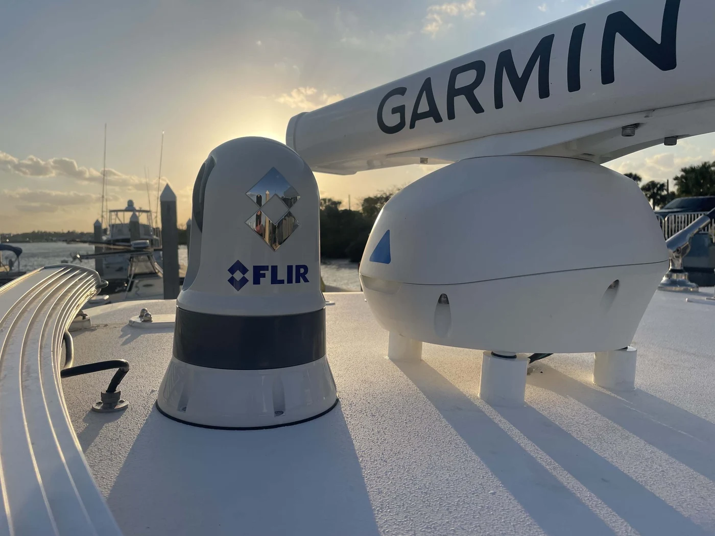 A FLIR camera and Garmin radar dome mounted on a boat's hardtop at sunset