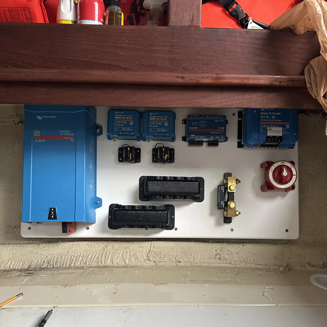A power system panel staged for installation, with a MultiPlus-II, dual MPPT solar controllers, Cerbo GX monitor, and Orion-Tr Smart charger mounted together